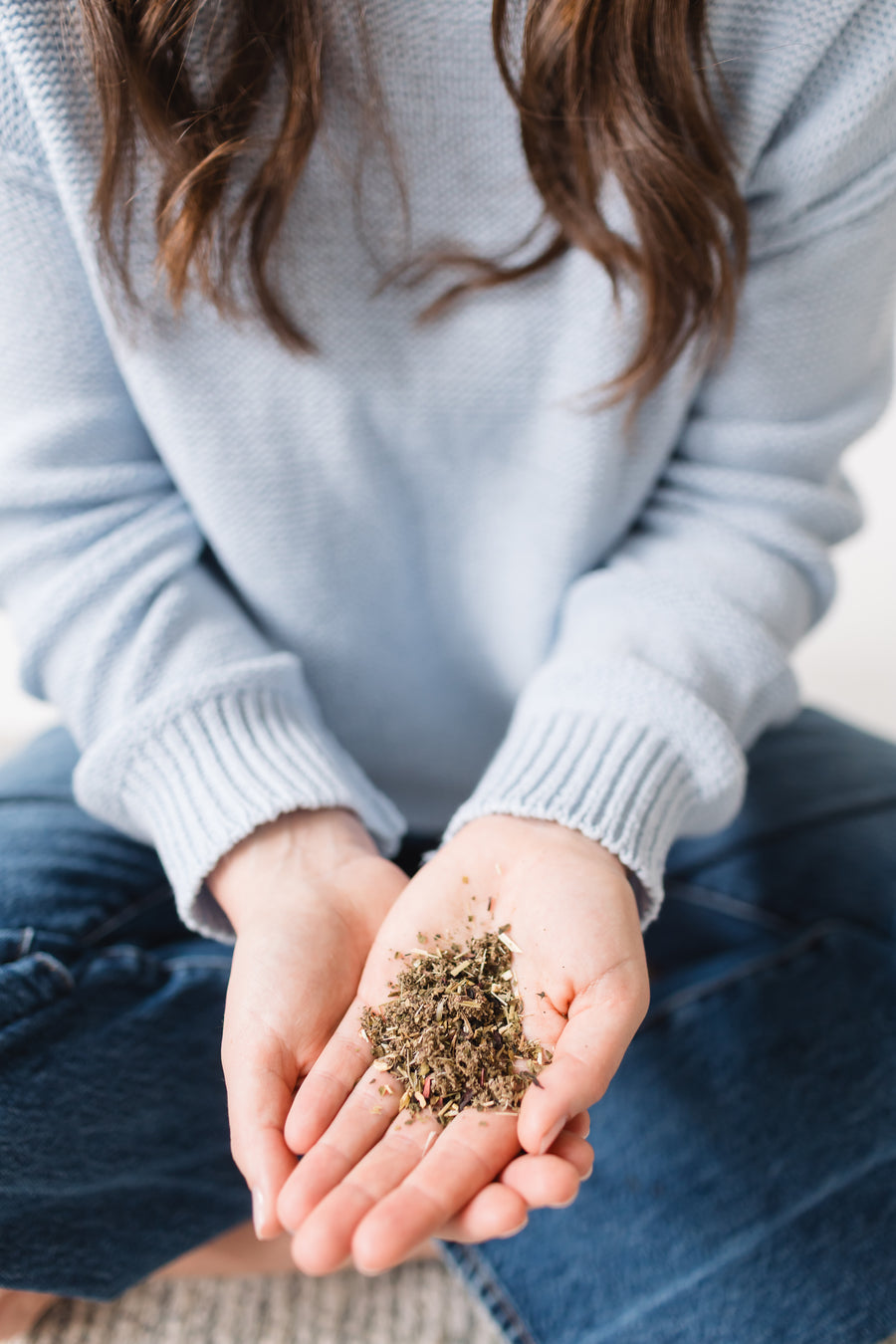Person holding a small amount of dried herbs in their hands
