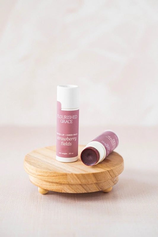Two lip balms on a wooden coaster with a light background